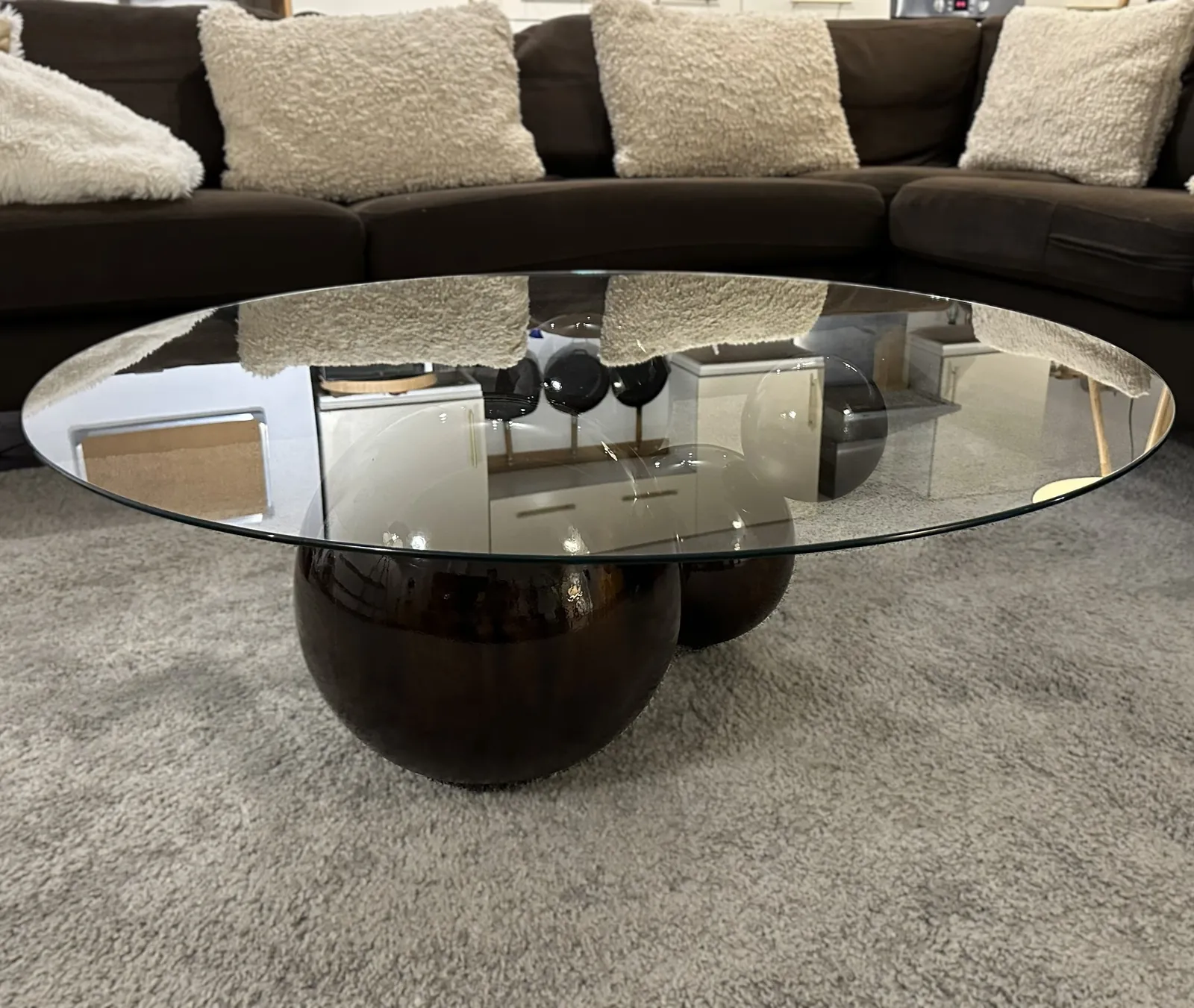The Orbital coffee table: a round glass top on black lacquered spheres, on a grey rug