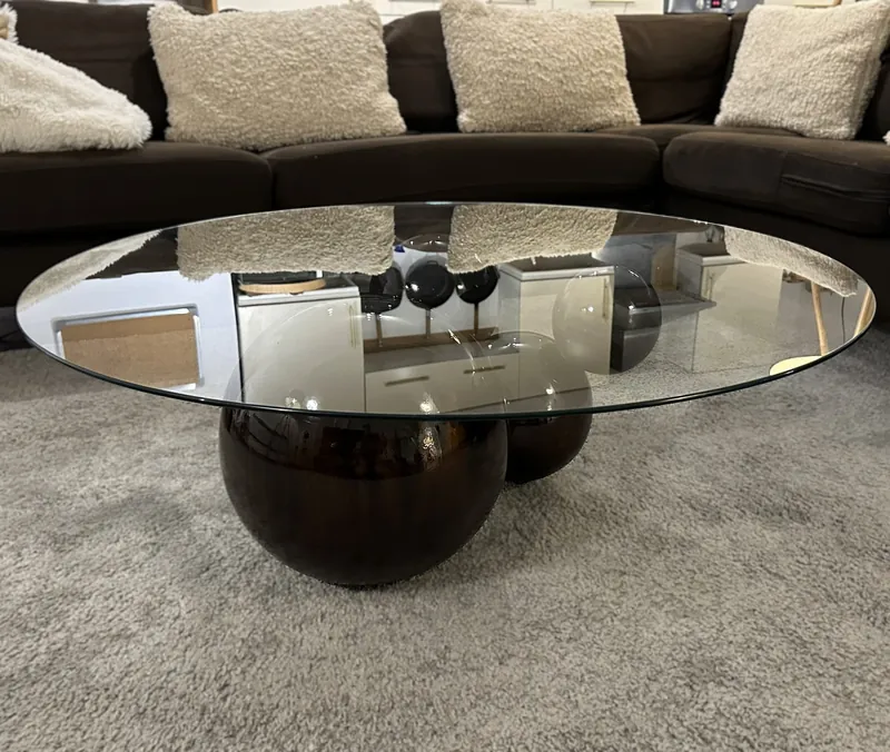 The Orbital coffee table: a round glass top on black lacquered spheres, on a grey rug
