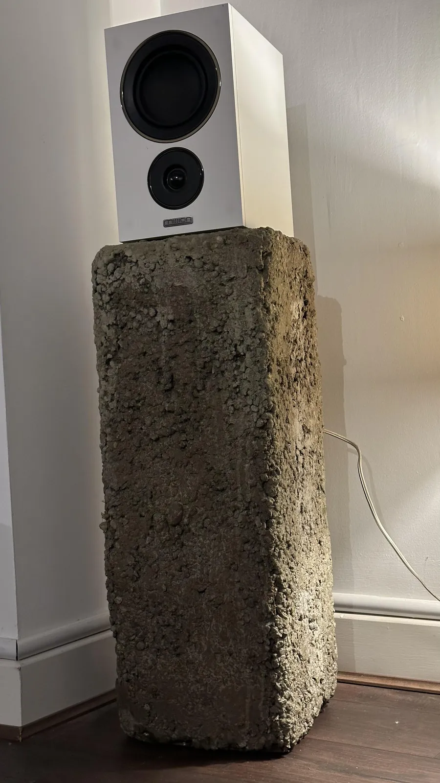 The Urban concrete plinth against a wall, a white speaker on top