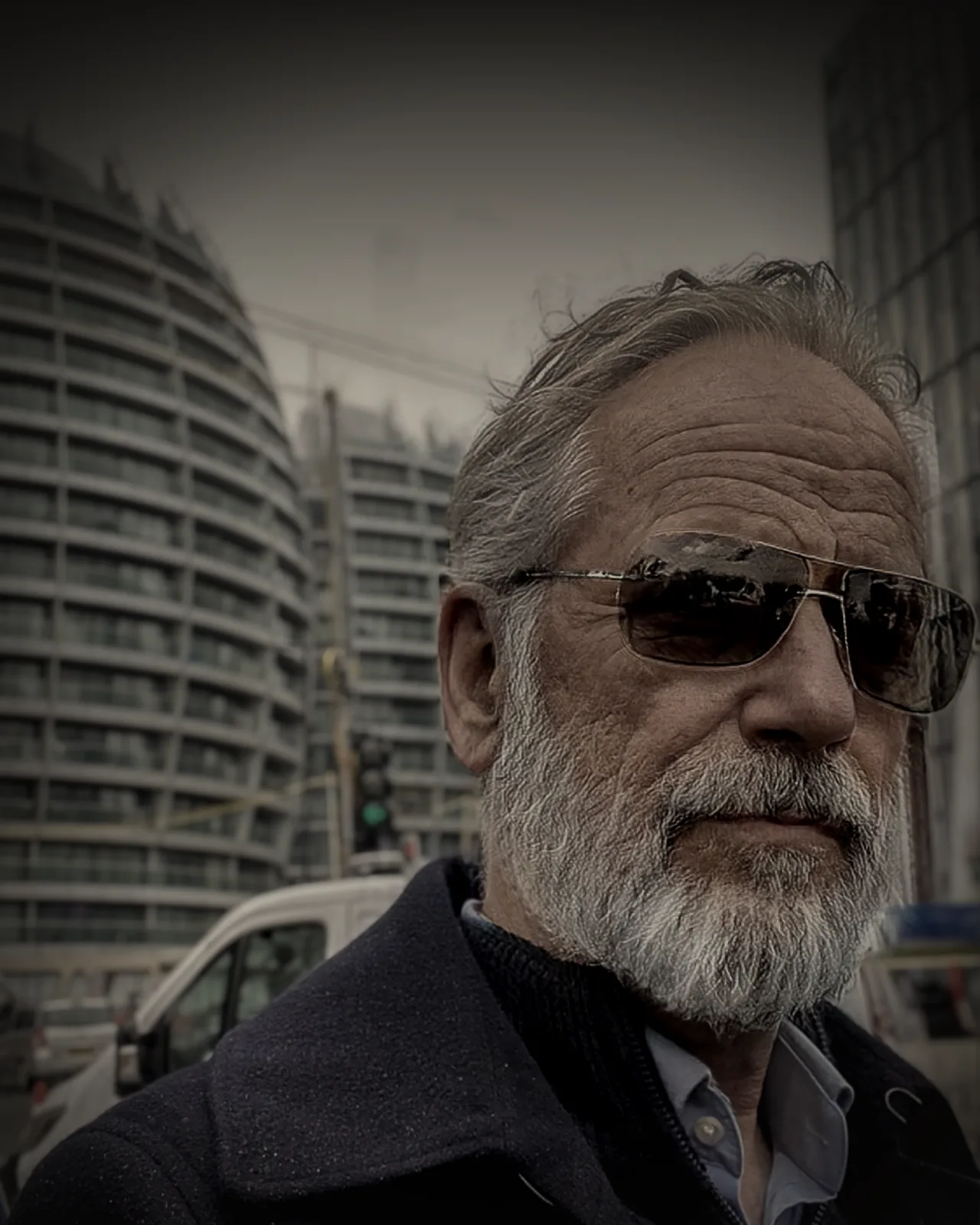 Vincenzo Luccivo, grey-bearded, in dark glasses and a navy coat, city towers behind him